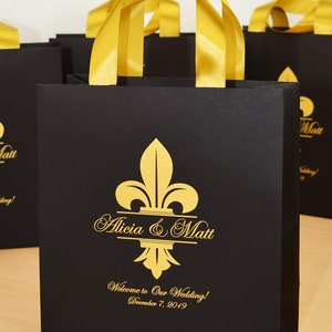 25 Fleur de lis Wedding Welcome bags, elegante bolso personalizado negro y oro con asas y nombres de cinta de raso, bolsas de regalos para los invitados