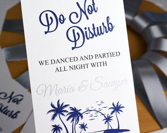 May include: White card with blue text that reads "Do Not Disturb" and "We danced and partied all night with Maria & Sawyer".  The card also features a blue illustration of palm trees and a beach with the text "Long Island, NY 07.28.2019".