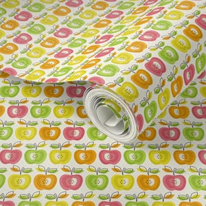 May include: A roll of wallpaper featuring a repeating pattern of stylized apples in shades of pink, orange, yellow, and light green on a white background. Each apple is outlined in black with a simple stem and leaf design.