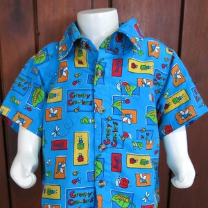 May include: A blue short-sleeved button-down shirt with a colorful print of bugs and the words "Creepy Crawlers".