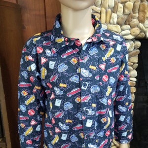Puede incluir: Una camisa negra de manga larga con botones con un estampado de coches, señales de tráfico y rayos.