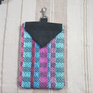 May include: A small, colorful, woven pouch with a black flap and a silver clip. The pouch has a striped pattern in shades of blue, pink, and black.