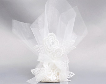 Könnte beinhalten: Ein weißer Organza-Geschenkbeutel mit einer zarten floralen Spitzenapplikation auf der Vorderseite. Der transparente Stoff ist oben mit einem passenden weißen Band zusammengebunden, was ein weiches, durchscheinendes Aussehen erzeugt.