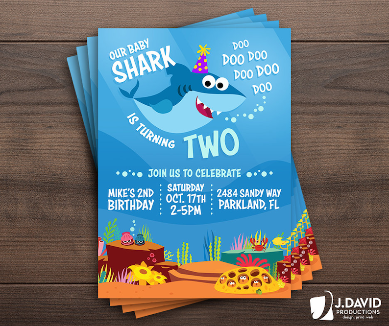 May include: A blue and orange birthday invitation with a cartoon baby shark wearing a party hat. The text reads "Our Baby Shark is Turning Two" and includes details for a party on October 17th.