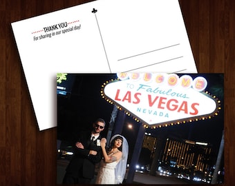 May include: A wedding postcard featuring a couple in front of the iconic "Welcome to Fabulous Las Vegas" sign. The groom is wearing a black suit and the bride is wearing a white wedding dress. The postcard has the text "Thank You" and "For sharing in our special day!" on the back.