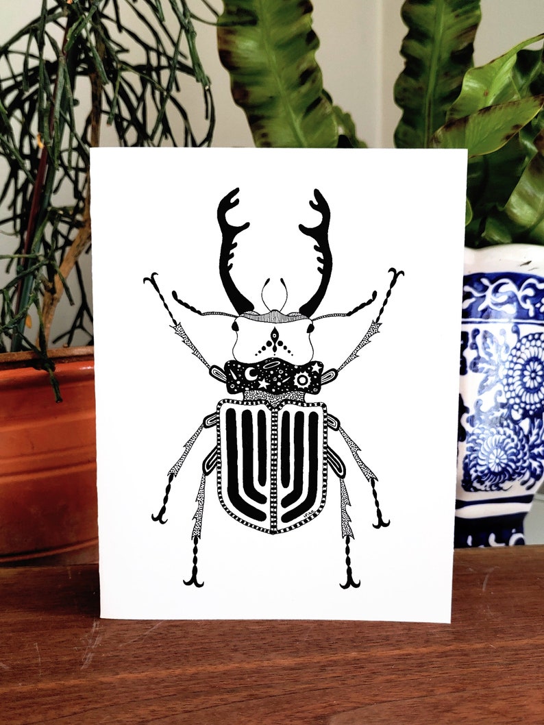 May include: Black and white line art illustration of a stag beetle with intricate details. The beetle has a large, ornate head with long, curved mandibles and a segmented body with a pattern of stripes and dots.