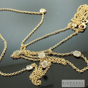 Puede incluir: Un collar de cadena de oro con múltiples hebras y diamantes de forma cuadrada. El collar está sobre una superficie negra.  Diamonds by Lauren.