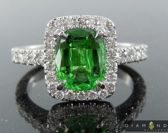 May include: A green gemstone ring with a halo of diamonds. The ring is set in white gold and has a polished finish.