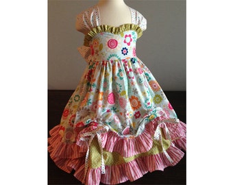 May include: A white dress with a floral print and a green, pink, and yellow ruffled skirt.