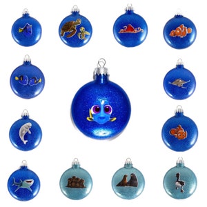 May include: Twelve blue and teal Christmas ornaments with various sea creatures and characters from the movie Finding Dory. The ornaments are decorated with glitter and feature characters like Dory, Nemo, Crush the turtle, and a seahorse.