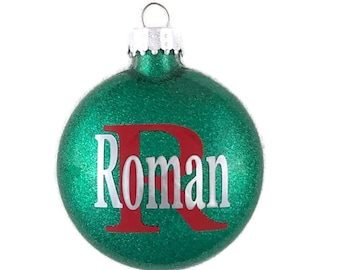 May include: Green glitter Christmas ornament with a red letter "R" and the name "Roman" in white lettering.