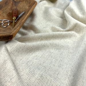 May include: A close-up of a white, textured fabric with a subtle pattern. The fabric is soft and has a slightly fuzzy texture.