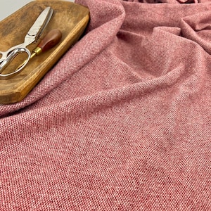 May include: A close-up of a red fabric with a textured weave. The fabric has a subtle sheen and a soft, drapey feel.