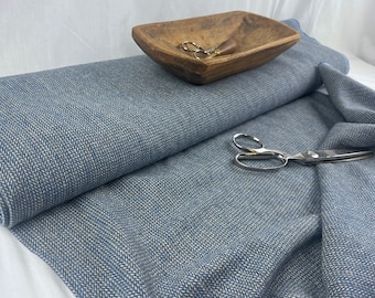 May include: A blue and white herringbone fabric with a subtle texture. The fabric is folded in half and laid on a white surface. A wooden bowl and a pair of scissors are also visible in the image.