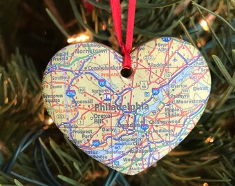 Op de afbeelding: Een hartvormige kerstversiering met een kaart van Philadelphia, Pennsylvania. De versiering is gemaakt van papier en heeft een rood lint aan de bovenkant.