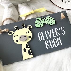 May include: A grey wooden sign with the text "OLIVER'S ROOM" in white. The sign features a yellow giraffe with black spots and two green leaf accents. The sign is decorated with a yellow ribbon and twine.