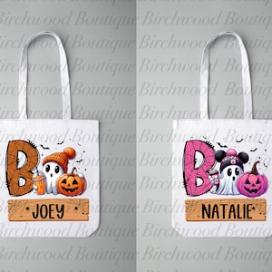 May include: Two white tote bags with personalized names, "JOEY" and "NATALIE", featuring a cute ghost holding a pumpkin and a cup of hot chocolate. The ghost is wearing a hat and scarf. The background is a pink and orange spiderweb with bats.