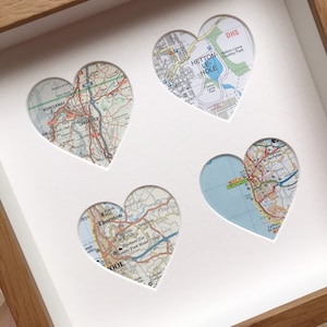 May include: A framed piece of art with four heart-shaped cutouts, each displaying a section of a detailed map. The maps show locations including Lancaster, Blackpool, and Hetton-le-Hole. The frame is light brown.