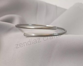 May include: A silver-toned metal bypass bracelet with a smooth, polished finish and tapered ends. The bracelet features a continuous, open-ended spiral design. The text zendiaz crafts is visible in the lower portion of the image.