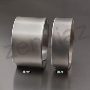 Op de afbeelding: Twee zilverkleurige metalen ringen. De grotere ring is 15 mm breed, de kleinere 8 mm. De ringen hebben een gladde, matte afwerking, tegen een donkere achtergrond.