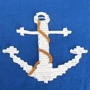 Peut inclure: Un fond en tissu bleu vif orné d'une ancre en crochet blanc. L'ancre est agrémentée d'une cordelette en crochet doré métallique qui s'enroule autour du montant vertical central de la structure de l'ancre, créant un contraste texturé.