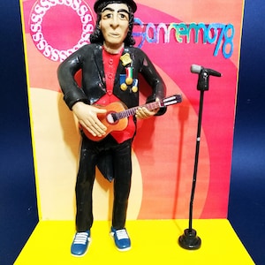 Può includere: Una statuetta di una persona vestita con un abito nero e un cappello a cilindro, che tiene una chitarra e sta in piedi su un palco giallo. Lo sfondo è rosso e arancione con il testo "Sanremo 78".