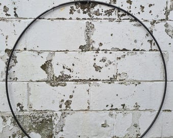 Op de afbeelding: Een grote, dunne, cirkelvormige metalen hoepel met een gladde, donker antracietgrijze afwerking. De hoepel is een eenvoudige, doorlopende ringstructuur met een uniforme dikte over de gehele omtrek, gepresenteerd als een enkelvoudig, onversierd geometrisch object.