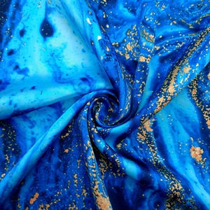 Puede incluir: Tela azul y dorada con un patr&oacute;n de m&aacute;rmol. La tela es suave y sedosa, y los colores son vibrantes.