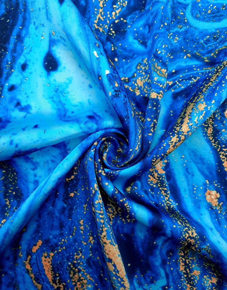 Puede incluir: Tela azul y dorada con un patr&oacute;n de m&aacute;rmol. La tela es suave y sedosa, y los colores son vibrantes.