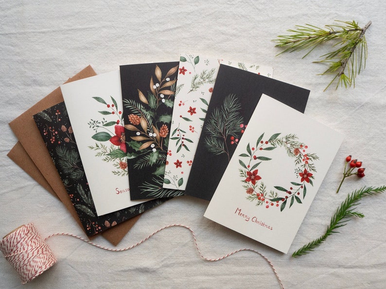 Set of 6 botanical Christmas cards with different branches and flowers on cream white and black backgrounds.