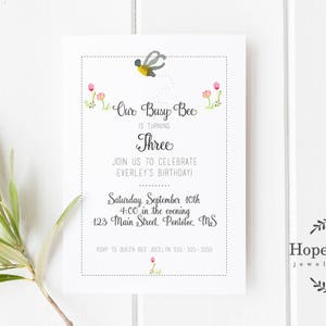 May include: A white invitation card with a bee illustration and the text "Our Busy Bee is turning Three. Join us to celebrate Everley's birthday! Saturday, September 10th, 4:00 in the evening, 125 Main Street,  Pentelic, MS."