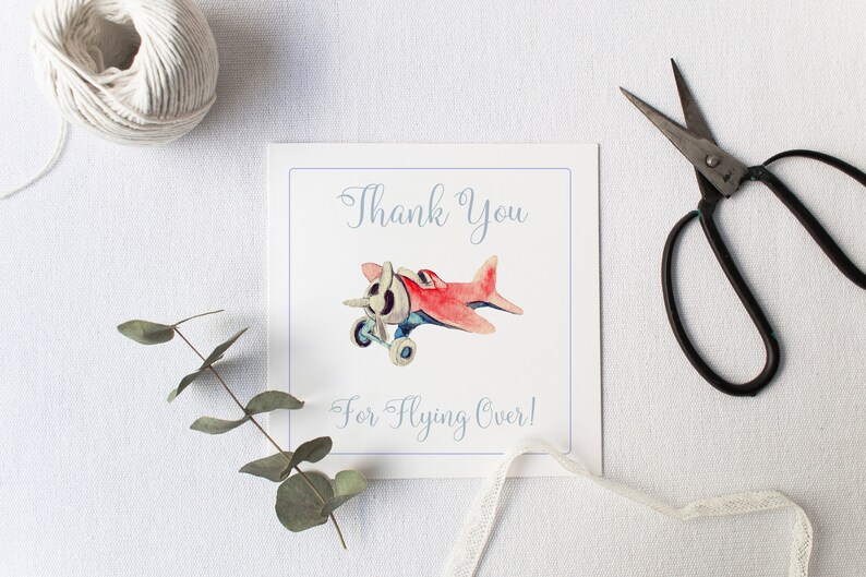 Puede incluir: Una tarjeta blanca con texto azul que dice "Gracias por volar por encima!" y una ilustraci&oacute;n de acuarela de un avi&oacute;n de juguete rojo con detalles azules.