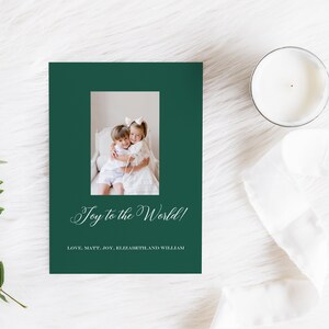 May include: A green Christmas card with a photo of two children hugging. The card reads "Joy to the World!" and "Love, Matt, Joy, Elizabeth, and William".