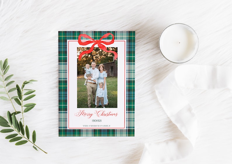 May include: A Christmas card with a green plaid background and a red bow. A family photo is in the center of the card with the text "Merry Christmas 2023 The Creek Family".