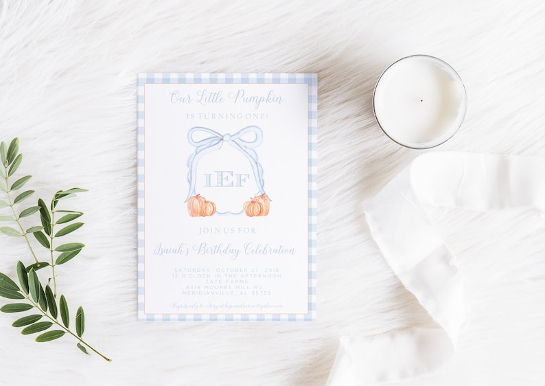 Op de afbeelding: Een blauwe en witte gingham-gepatroneerde uitnodigingskaart met een aquarel-illustratie van een krans met een strik en pompoenen. De tekst op de kaart luidt "Onze kleine pompoen wordt &eacute;&eacute;n!" en "Doe mee met de verjaardagviering van Isaiah".
