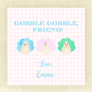 May include: A pink and white gingham background with the text "Gobble Gobble, Friend!" in blue. Three watercolor turkeys with pink, blue, and green feathers are arranged in a row. The text "Love, Emma" is written in blue cursive below the turkeys.