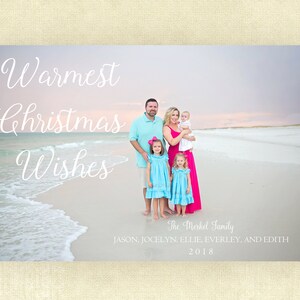 May include: A Christmas card featuring a family of five standing on a beach. The card has the text "Warmest Christmas Wishes" and "The Merkel Family" with the names of the family members and the year 2018.