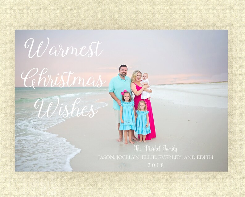 May include: A Christmas card featuring a family of five standing on a beach. The card has the text "Warmest Christmas Wishes" and "The Merkel Family" with the names of the family members and the year 2018.