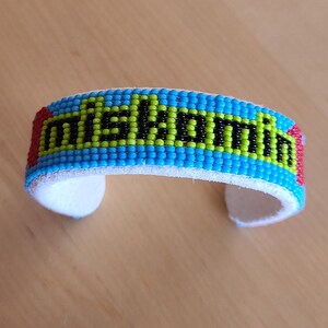 May include: A blue, green, red, and black beaded bracelet with the word "MELBOURNE" spelled out in black beads.
