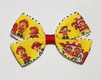 May include: Yellow and white bow with a red center, featuring a repeating pattern of cartoon firefighters and fire trucks.