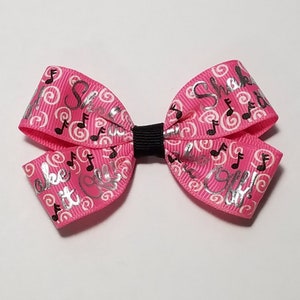 May include: Pink hair bow with a silver and white musical note pattern and the text "Shake it Off" on it.