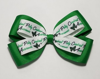May include: A green and white ribbon bow with the text "Cerebral Palsy Awareness" and butterfly graphics. The bow is layered, with a green base and a white ribbon on top.