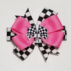 May include: A pink and black checkered hair bow with a white checkered flag design in the center.