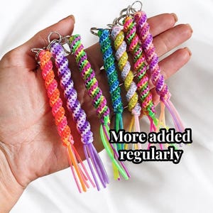 May include: A collection of six spiral-braided plastic lanyards with metal key rings, featuring vibrant neon color combinations including orange, purple, green, blue, and yellow, with the text More added regularly printed on the image.