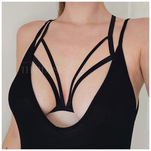 May include: Black lingerie with a criss-cross strap design. The straps are made of a thin, stretchy material and are adjustable. The lingerie is made by the brand "Third & Sin".