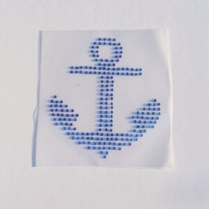 May include: A blue anchor design made of rhinestones on a white fabric background.
