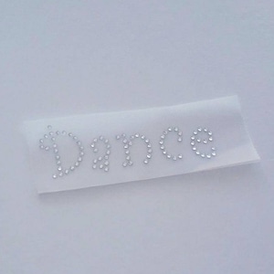 May include: White fabric headband with the word "Dance" spelled out in clear rhinestones.