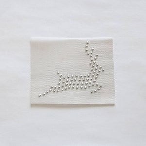 May include: A white fabric patch with a silver rhinestone design of a reindeer.