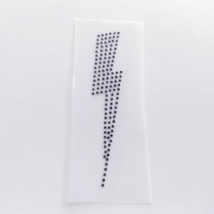 Könnte beinhalten: Ein schwarzer Strass-Bügelaufkleber in Form eines Blitzes.