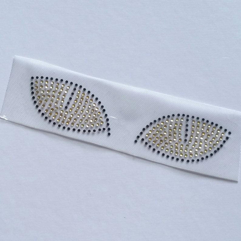 K&ouml;nnte beinhalten: Zwei aufb&uuml;gelbare Patches in Blattform mit goldenen und schwarzen Strasssteinen.
